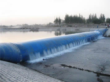 A blue inclined rubber dam across a river