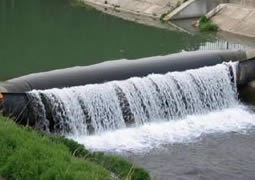 A black pillow-like bookend rubber dam is functioning across a river.