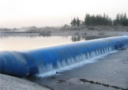 A blue inclined rubber dam across a river